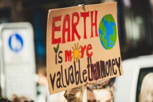 Picture of a cardboard sign that says Earth is More Valuable Than Money