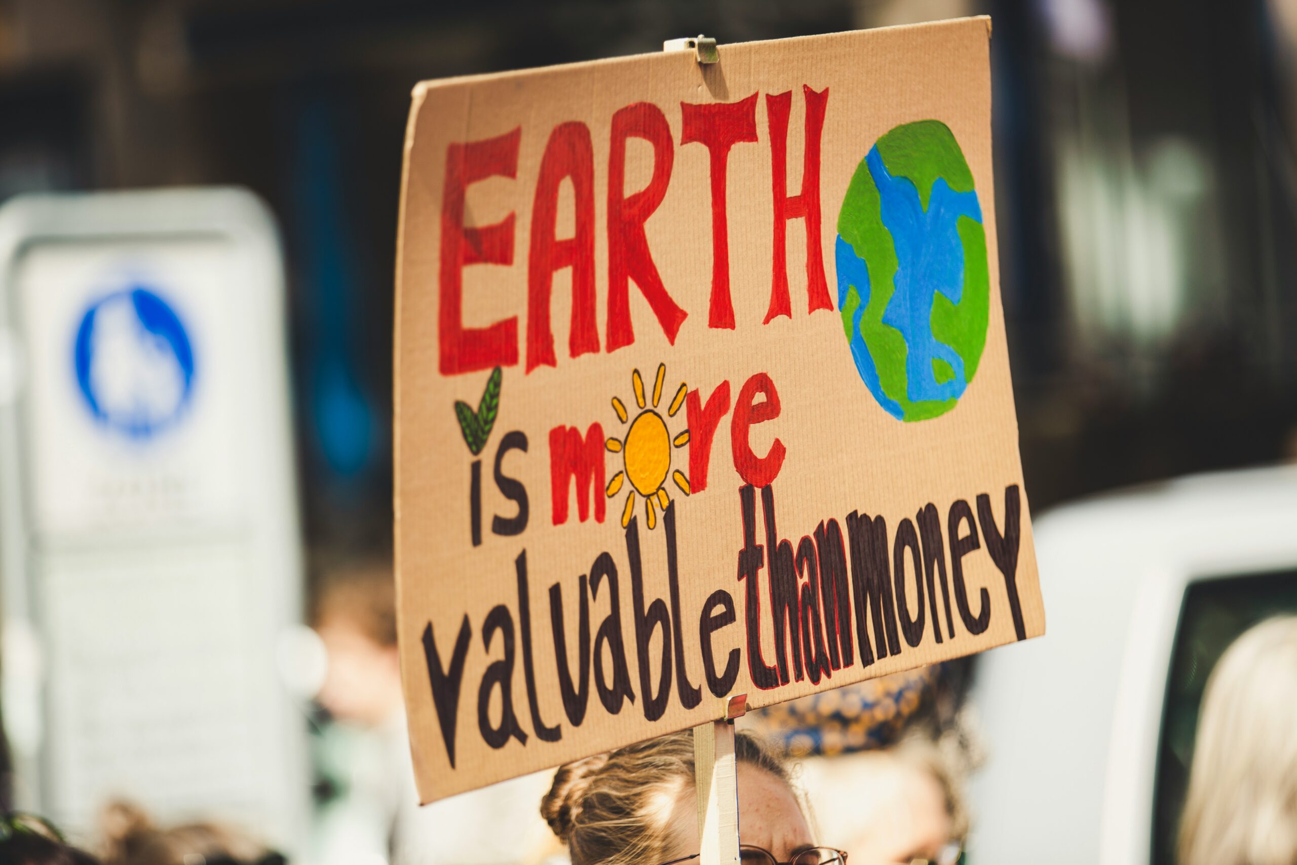 Picture of a cardboard sign that says Earth is More Valuable Than Money