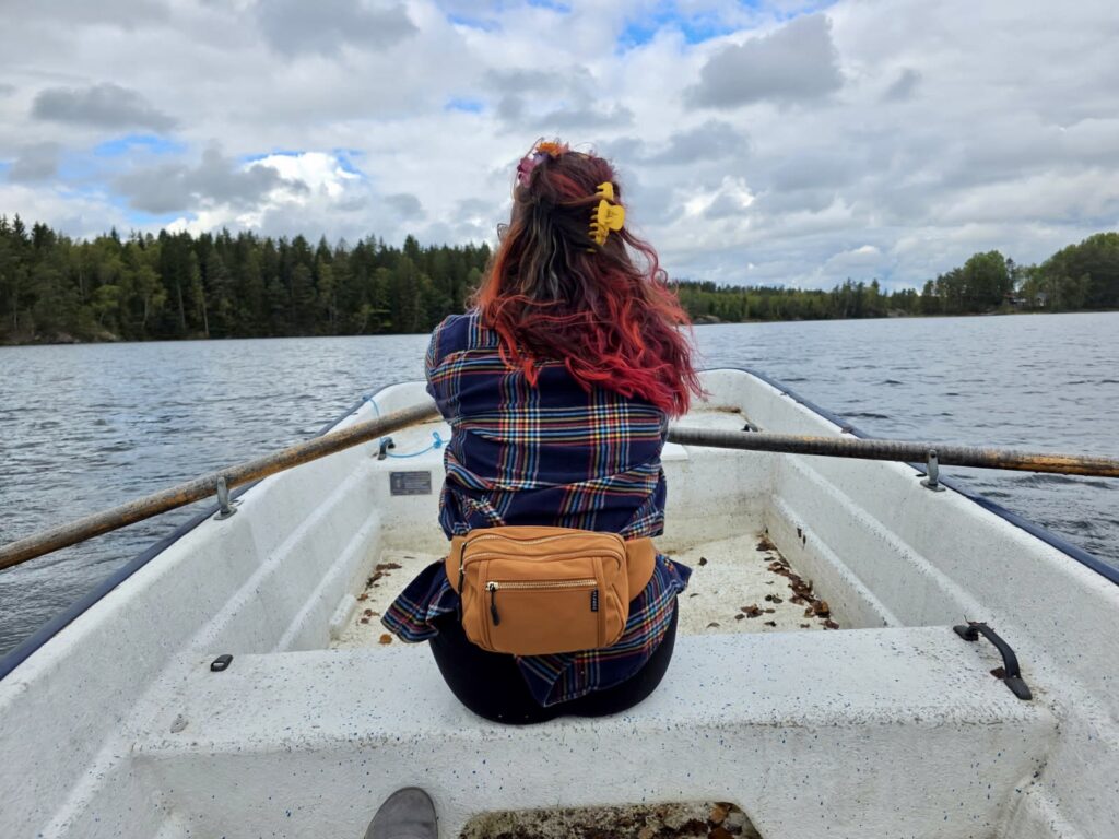 Back of a woman in a flannel shirt as she rows a white boat.