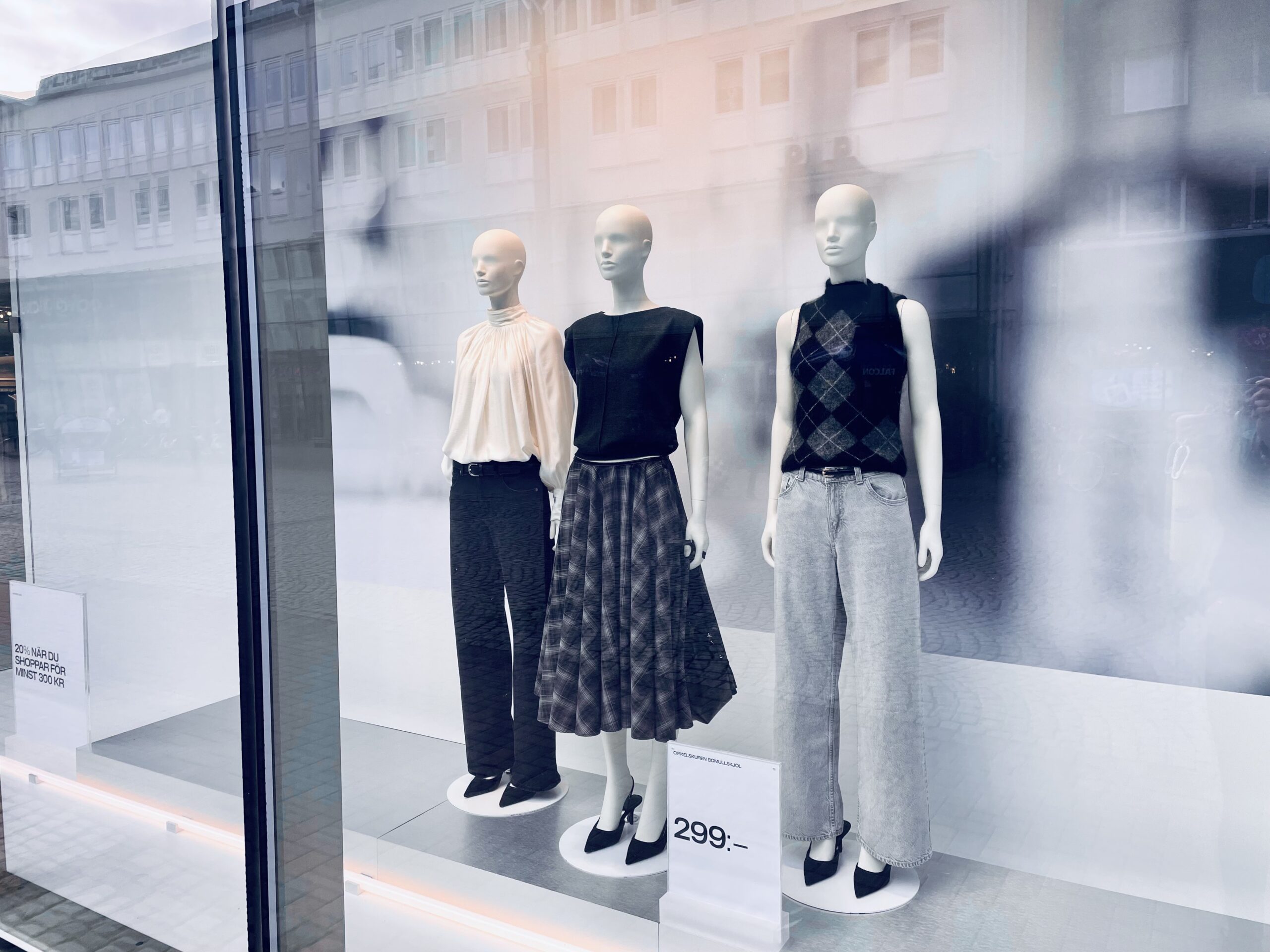 Photo of three white mannequins in a storefront wearing black and white comfortable clothing.