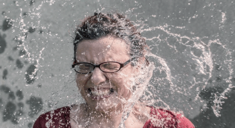 woman wearing glasses getting splashed in the face with water