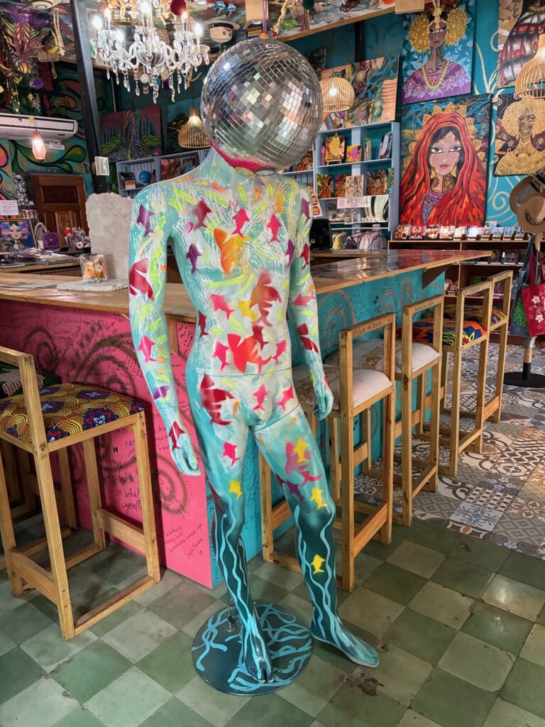 Photo of the Artesenias Panamà Vida Mía art studio. A mannequin painted blue with fish on it and a disco ball for a head, stands in the foreground.