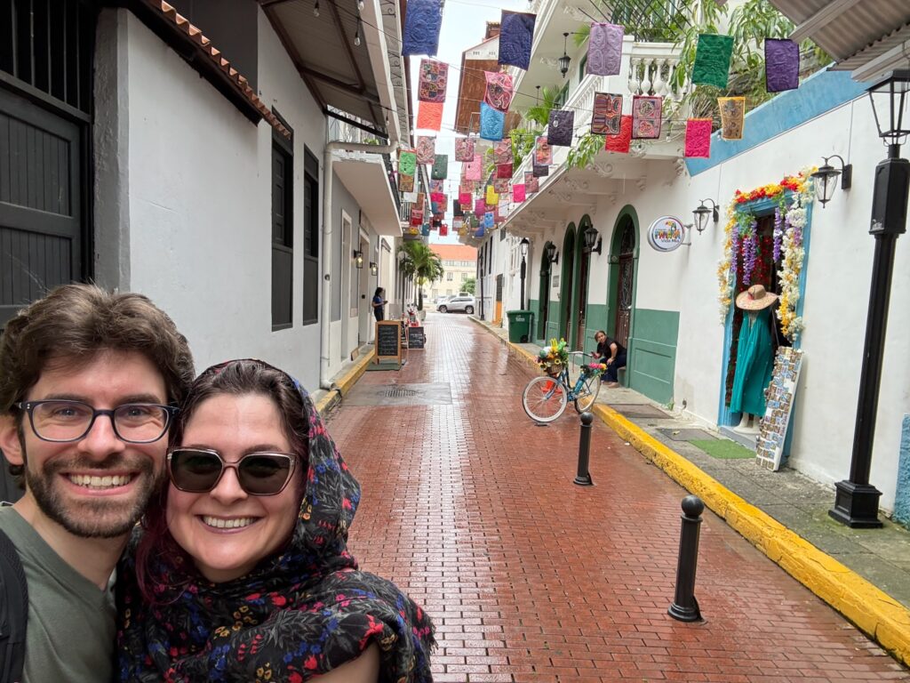 Man and woman on a street decorated with colorful molas.