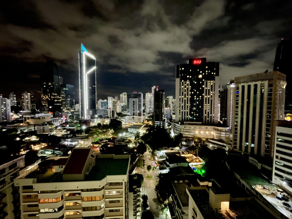 Skyscrapers of Panama City at night. Background is a dark navy sky with wisps of white clouds.