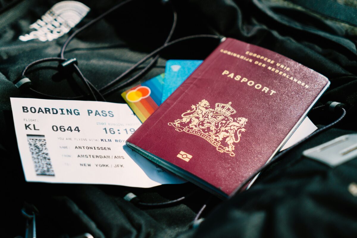 Picture of a passport, credit cards and plane ticket on top of a black backpack.